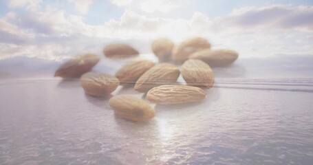 Naklejka premium Floating cluster of whole almonds hovering above calm coastal sea at sunrise, reflecting on ripples