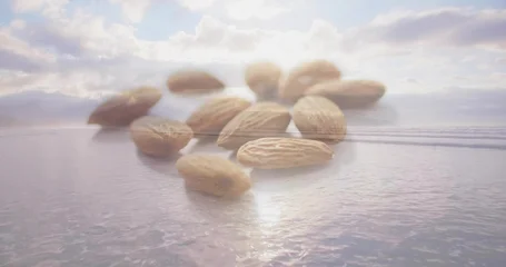 Fotobehang Zee & Oceaan Floating cluster of whole almonds hovering above calm coastal sea at sunrise, reflecting on ripples  © vectorfusionart