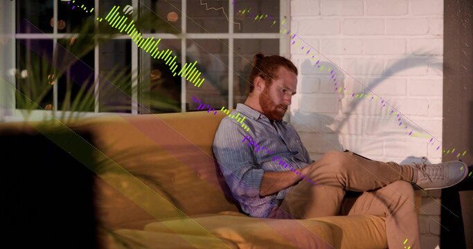 Sitting man in striped shirt writing on tablet in home lounge, with mustard sofa