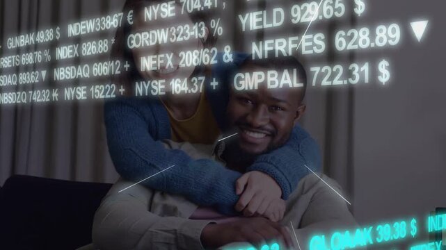 Woman approaching man hugging affectionately on couch, FOREX NASDAQ ticker drifting revealing faces