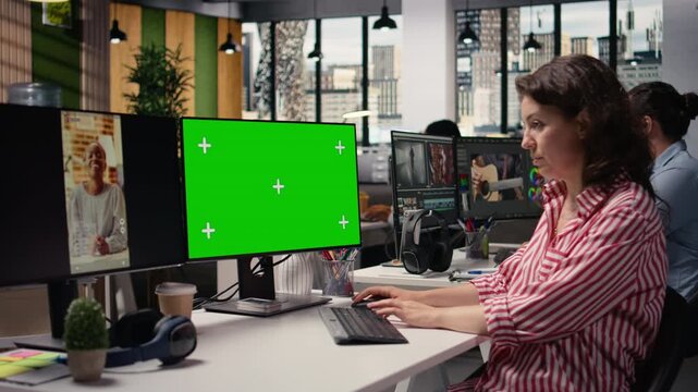 Mockup green screen next to media short clips on PC monitor, male production specialist checking online content on platforms. Boosting monetization numbers based on marketing insights.