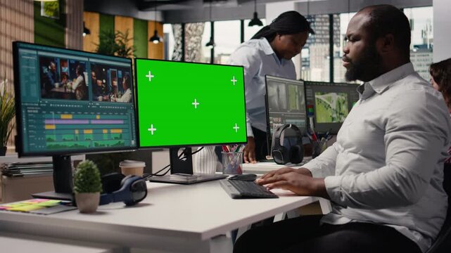Chroma key and video footage interface on dual monitors, black man editor in creative office performing post production. PC shows montage editing tools and raw clips, cinematic content.
