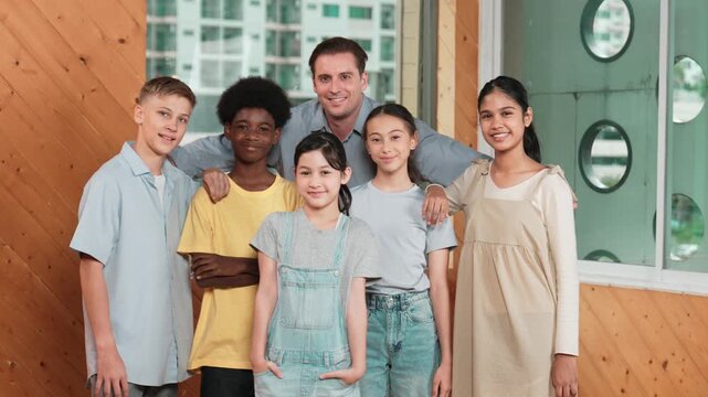 Happy teacher and diverse student standing while smilling to camera. Professional smart instructor with high school children with mixed races in casual outfit pose at camera with cheerful. Edification