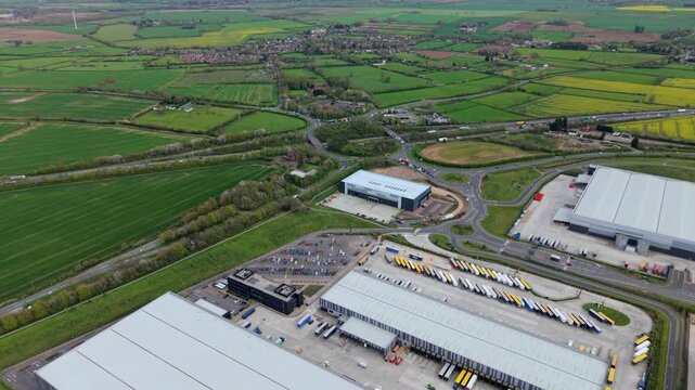 Aerial view of Appleby Magna Industrial Park with large warehouses, parked trucks, and green fields in Appleby Magna, England, United Kingdom.