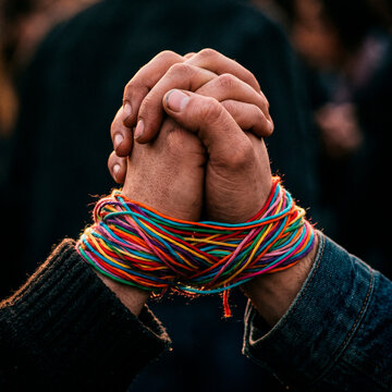 Unidad y diversidad humana: Dos personas uniendo sus manos, conectadas por hilos de colores vibrantes que simbolizan la solidaridad.