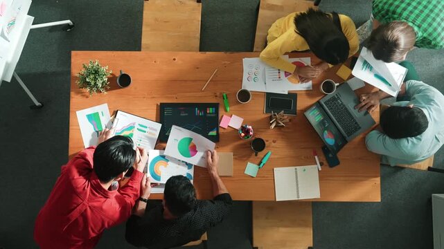 Top view of smart businessman present marketing idea at meeting while group of investor listening and planning strategy while looking at stock market chart or data analysis. Time lapse. Convocation.