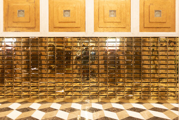 Naklejka premium Golden mailbox wall, mirrored metal mailbox grid in lobby with geometric floor and warm light