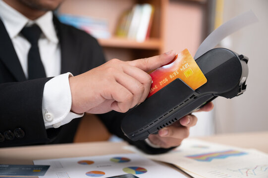 Businessman payment credit card debit card card reader card machine pos terminal transaction finance office Businessman processing payment with credit card pos terminal, closeup hand holding card