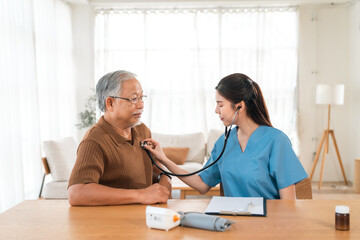 Fototapeta premium Caregiver with Asian senior patient, elderly man nurse home visit medical checkup listening heart blood pressure care room