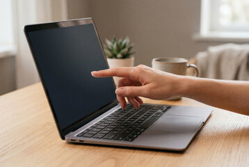 Fototapeta premium Human hand pointing at laptop screen on wooden desk