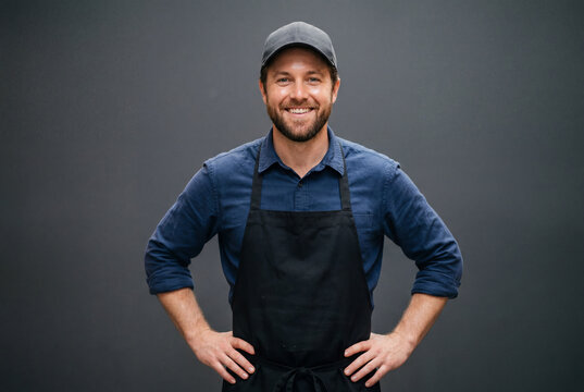 Smiling male service worker in black apron and cap