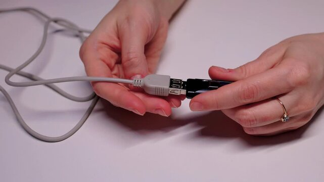 Closeup of precise insertion into black adapter on white background. Instructional scene demonstrating careful alignment of flash drive with USB extension port on clean surface