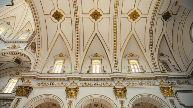 Symmetrical view of an ornate cathedral interior in Altea, Spain, featuring repeating arches, golden details and elegant classical architecture in bright light.
