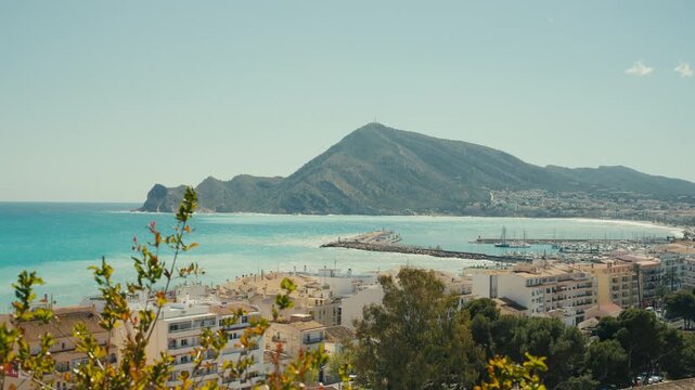 Panoramic coastal view of Altea, Spain featuring turquoise sea, marina harbor, and surrounding mountains. Bright Mediterranean scenery with a relaxed and inviting atmosphere.