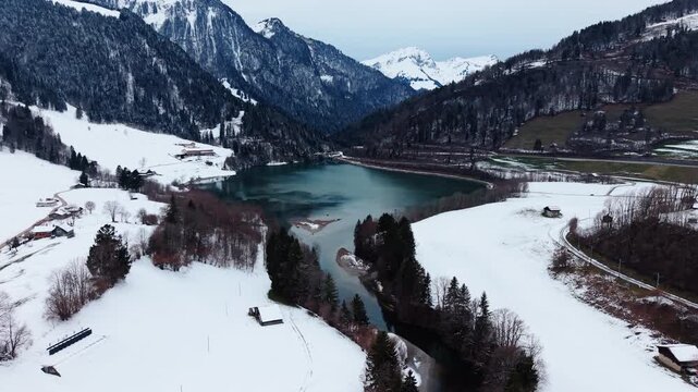 Aerial: Sarine river and Lake Vernex with snow in winter in Rossiniere, Riviera-Pays-d'Enhaut district, canton of Vaud, Switzerland, pan drone shot