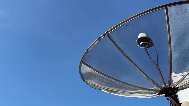 Satellite dish antenna standing under blue sky in residential area, captured low angle in calm morning atmosphere showing communication technology.