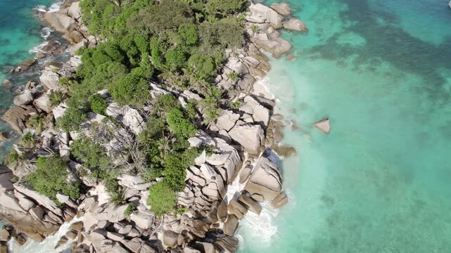 Bird eye rotating drone of cocos island, docked catamaran and lux yacht, lush untouched nature, granite stones, clear turquoise water, Seychelles 006 30fps