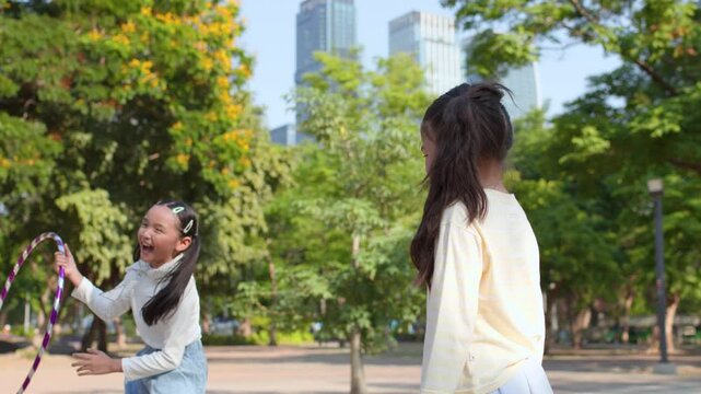 Two Young Asian Girls Playing With Hula Hoop In Bangkok Park