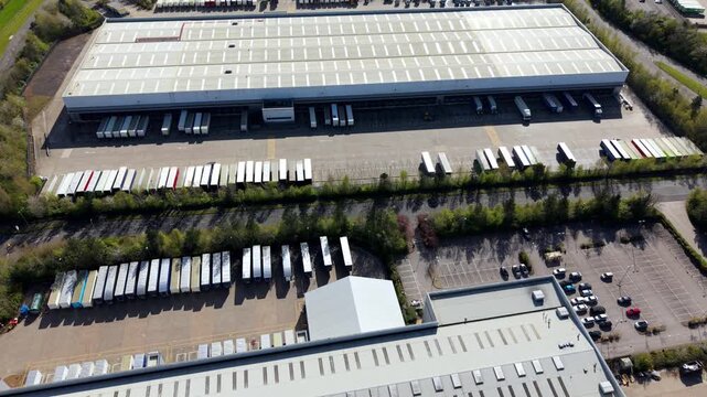 Aerial view of large industrial warehouses with loading docks and rows of parked semi-trailers in Magna Park, England, United Kingdom.