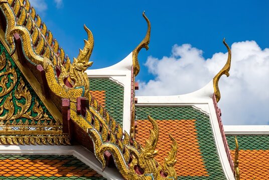 An extreme close-up architectural detail photograph of overlapping multi-tiered Thai temple roof eaves, showcasing intricate Chofa sky tassel finials in gilded bronze shaped as Garuda bird heads.