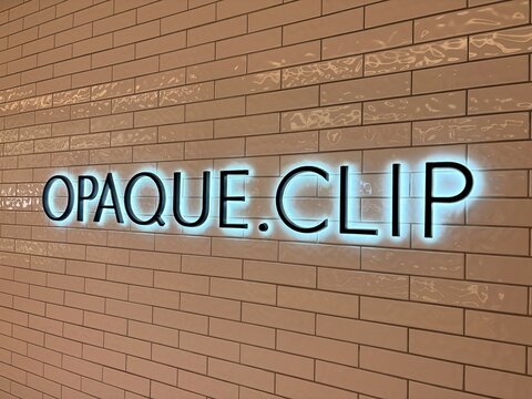 OPAQUE.CLIP fashion store signage with upside down neon letters on a glossy tiled wall interior at LaLaPort Toyosu shopping mall - Tokyo, Japan, January 22, 2026