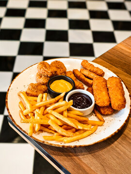 Fried appetizers platter with french fries, chicken nuggets, and fish fingers.