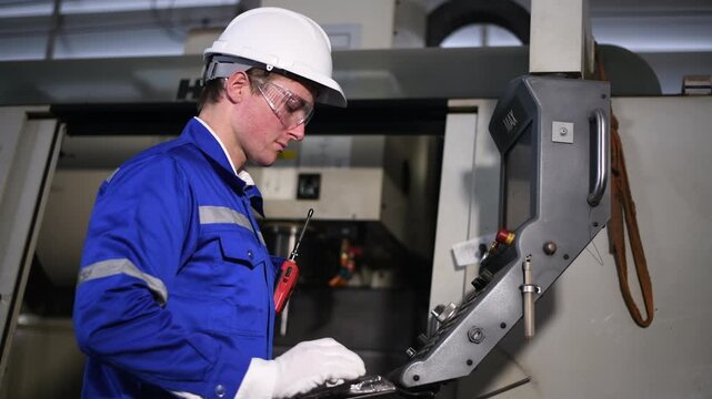 Industrial worker operating CNC lathe machine control panel using tablet monitoring and adjustments manages precision machining processes engineering metalworking and production industries.