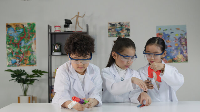 Three Asian Children in Lab Coats Conducting Science Experiment with Magnets