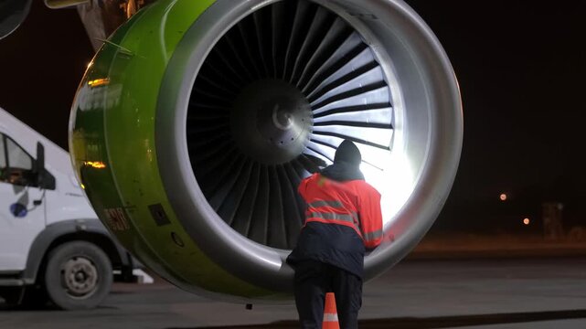Airplane jet aircraft engine technic man inspection. Airport terminal technician worker man airline maintenance ground crew aircraft. Safety at evening night.