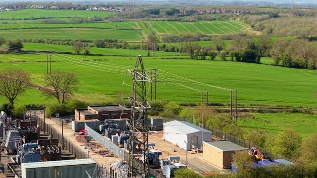 Aerial view of Coalville Substation with electrical pylons and transformers surrounded by lush green fields and trees in Coalville, England, United Kingdom.
