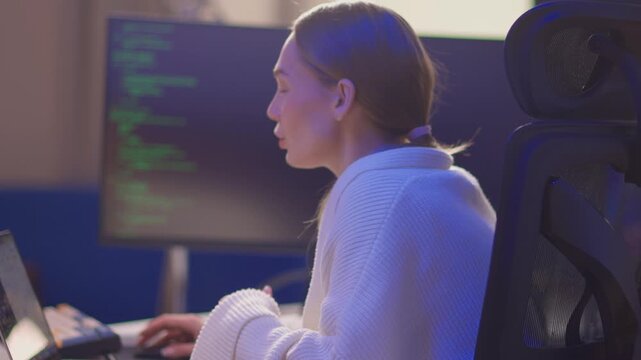 Female coder working. Female developer studying terminal output late at night. Dedicated woman engaged in remote software development and troubleshooting during nighttime hours