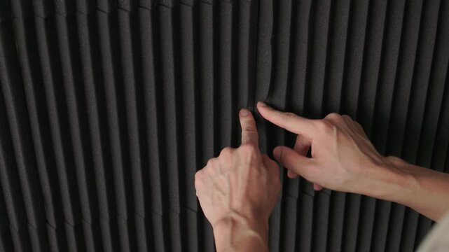 Soundproofing test on acoustic board. Evaluating sound insulation with acoustic panel testing. Technician assesses soundproofing effectiveness of acoustic panels in studio