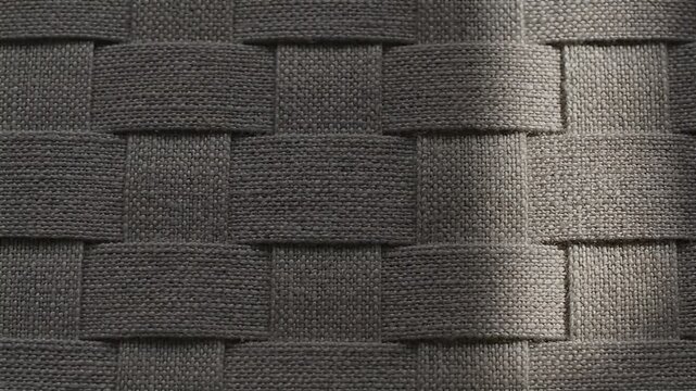 Close-up of textured woven fabric with a basket weave pattern and dramatic shadow play