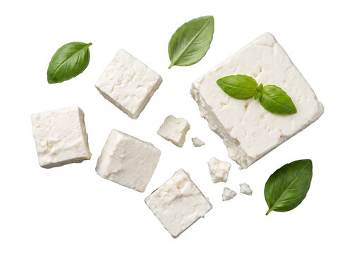 White feta cheese cubes, some crumbled, with fresh aromatic basil leaves scattered on a transparent background.