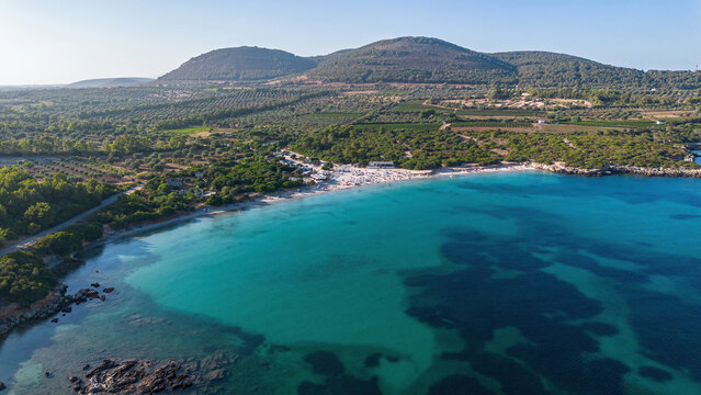 Aerial panoramic view of the crowded Lazzaretto beach and bay with crystal clear turquoise waters near Alghero, Sardinia, Italy