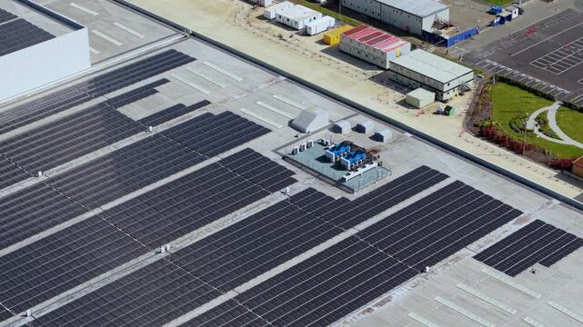 Aerial view of solar panels installed on the roof of a new build supermarket distribution centre with construction offices and parking in Nuneaton, England, United Kingdom.