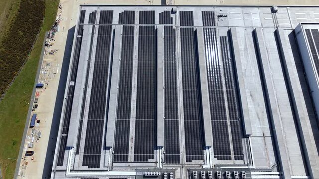 Aerial view of solar panels installed on the roof of a new supermarket distribution centre with construction materials nearby in Nuneaton, England, United Kingdom.