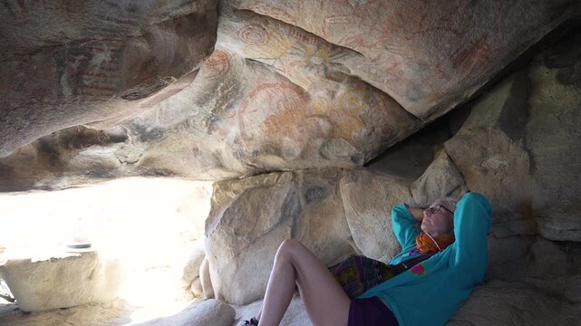 A mature woman hikes in the Catavina desert, discovering ancient cave paintings and engaging with the archaeological site.