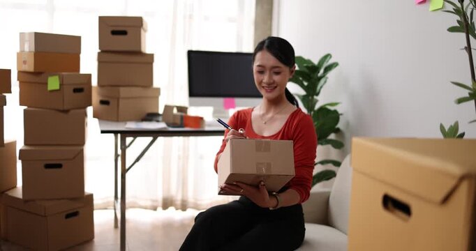 Woman working, online shop owner checking orders from websites on the internet to confirm orders with customers who have ordered them and packing them for delivery. Concept of selling products online.