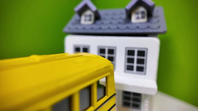 Concept of Yellow toy school bus driving away from home picking up kids.