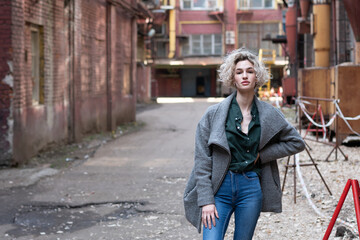 Naklejka premium Young beautiful woman posing in a gray coat outside