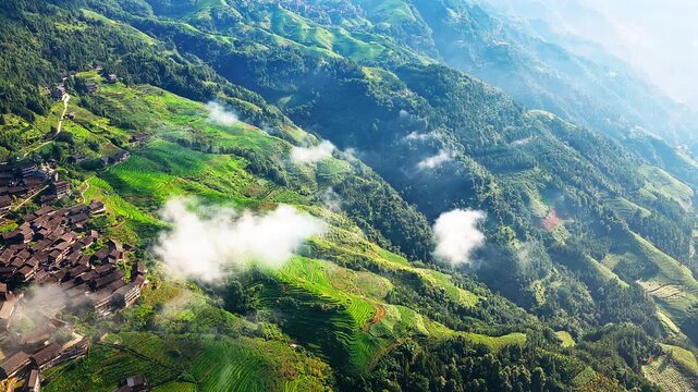 Stunning aerial view of green terraced rice fields with mist and clouds over mountain villages in Guilin, China