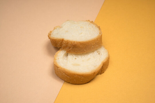 Two Slices of White Bread Stacked on a Split Color Background