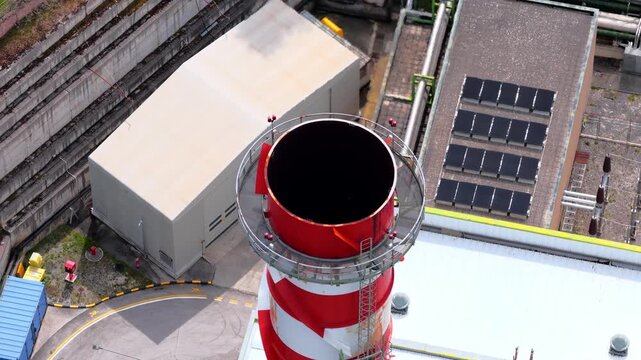 Aerial view of a red and white striped industrial chimney with solar panels and factory buildings in Bussi sul Tirino, Abruzzo, Italy.