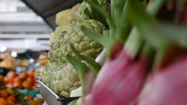 Sugar apple fruits Annona squamosa stacked in a pile with other tropical fruits visible behind. Exotic fruit, farmers market.