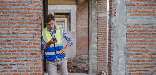 Construction Worker Using Mobile Near Brick Wall © photobyphotoboy