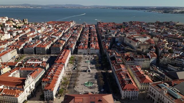 Aerial view of Rossio Square with its central monument and historic red-roofed buildings leading towards the Tagus River in Lisbon, Lisbon, Portugal.