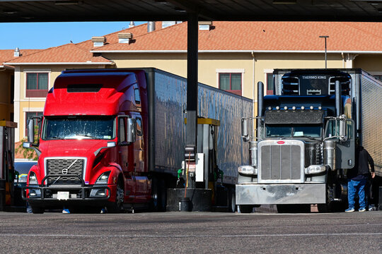 Semi-trucks refueling at fuel pumps at a truck stop, representing long haul transportation, diesel supply, and commercial freight logistics