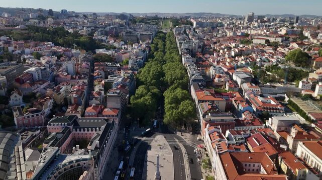 Aerial view of Avenida da Liberdade with its lush green trees and historic red-roofed buildings under a clear blue sky in Lisboa, Lisboa, Portugal.