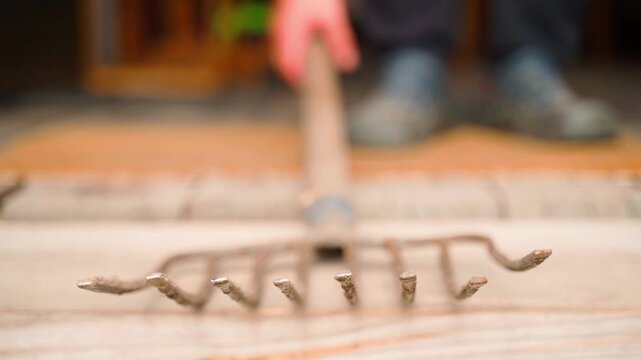 Farmer picking up garden pitchfork on blurred background